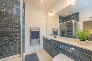 a bathroom with a sink and a shower with blue tiles at Hendre-Feinws in Pwllheli +31 photos
