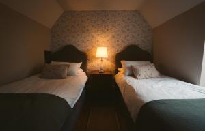 deux lits dans une chambre avec une lampe au mur dans l'établissement Longford Holiday Red Rose Self Catering Cottage, à Longford