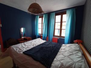 a bedroom with a bed with blue walls and windows at maison au charme rétro, équipée et tranquille in Abbeville