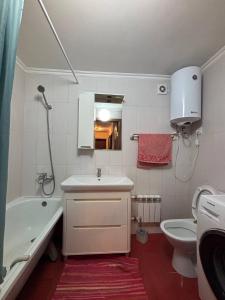 a bathroom with a sink and a tub and a toilet at Ермекова in Karagandy
