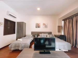- une chambre avec 2 lits et une télévision sur une table dans l'établissement Ombak Rileks Palace, à Malacca
