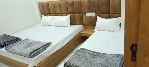 two beds in a small room with white sheets and pillows at Hotel Gokul in Ujjain