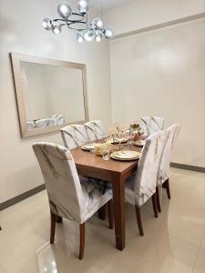 - une table à manger avec des chaises blanches et un miroir dans l'établissement Rea's Pad, à Sampong 3 autres photos