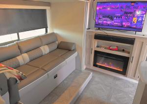 ein Wohnzimmer mit einem Sofa, einem TV und einem Kamin in der Unterkunft DDs Country Camper in Reedley
