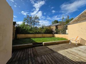 una terrazza in legno con una sedia sopra di Charmante maison de pierre rénovée a 5min de Charleville-Mézières a Saint-Marceau