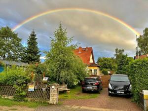 un arcobaleno nel cielo sopra una casa con auto parcheggiate di Ferienwohnung, Apartment, Pension - Berlin Neuenhagen a Niederheide