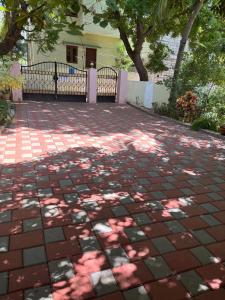a brick patio with trees and a house at Jeyaraj's Guest House in Samayanallūr