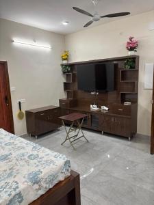 a bedroom with a flat screen tv and a bed at Jeyaraj's Guest House in Samayanallūr