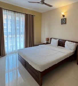 Un dormitorio con una cama grande y una ventana grande. en Luxury 2BhK by Cocopalm BnB, 