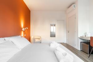 a bedroom with a white bed and an orange wall at Carducci Collection in Bologna