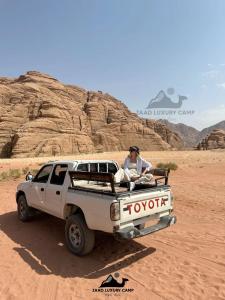 a man sitting in the back of a truck in the desert at Wadi Rum ZAAD luxury Camp in Wadi Rum