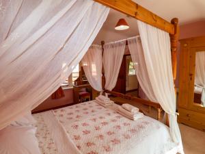 a bedroom with a canopy bed with white curtains at Coachman's Cottage in Henley