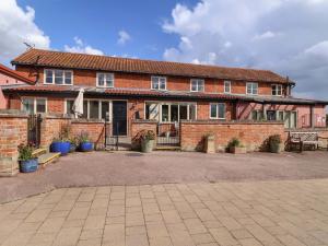 a brick house with a courtyard in front of it at Coachman's Cottage in Henley