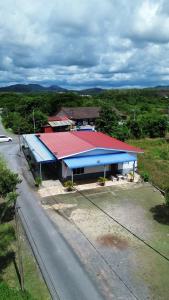a building with a red and blue roof next to a road at RUMAH INAP 09 in Arau
