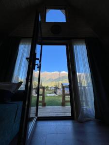 a door to a room with a view of a yard at Mestia Sunrise Cottage - 1BR Cosy Stay in Svaneti in Mestia +15 photos