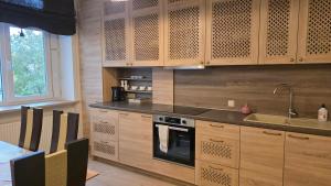 a kitchen with wooden cabinets and a sink and a stove at Vytauto Apartments in Šiauliai +12 photos