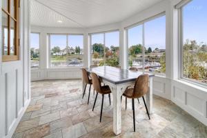 a dining room with a table and chairs and windows at Luxury Home with Harbor Views Hot Tub Walk to North Beach Dog Friendly in South Haven