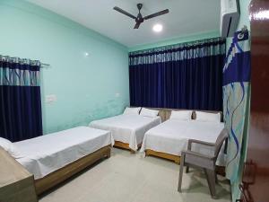 a room with two beds and a ceiling fan at Shree DashbhujaNath Stays in Ujjain