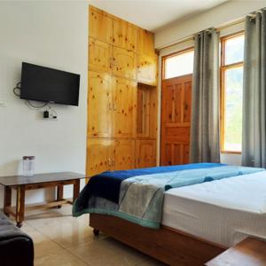 Un dormitorio con una cama y un televisor en la pared. en Hotel Midway Inn, en Jagatsukh