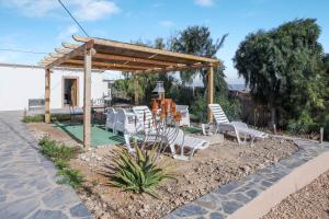 a patio with white chairs and a wooden pergola at Villa Luna Wifi Fibra in Lajares