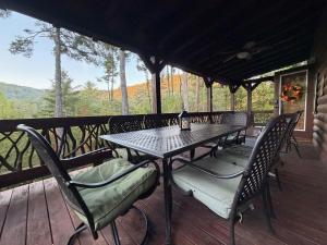 a table and chairs on a deck with a view at The cozy Lazy Laurel with year-round mountain views, hot tub, fire pit in Cherry Log