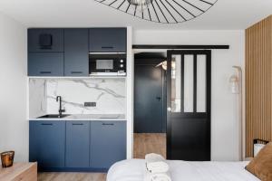 a kitchen with blue cabinets and a sink at Horizon bleu depuis un studio unique in Carnac +4 photos