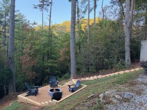 eine Terrasse mit zwei Stühlen und einer Feuerstelle im Wald in der Unterkunft The cozy Lazy Laurel with year-round mountain views, hot tub, fire pit in Cherry Log + 17 Fotos