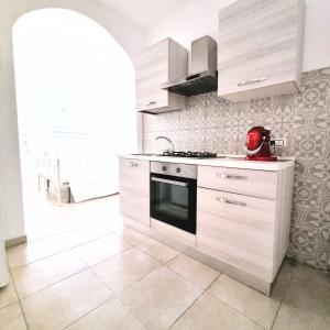 a kitchen with white cabinets and a stove at casa vacanza Terra del Primitivo in Manduria