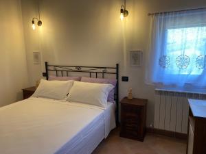 a bedroom with a bed with white sheets and a window at Casale Col di Massa Residenza di campagna in Costacciaro