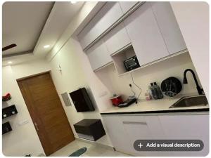 a small kitchen with white cabinets and a wooden door at Hello Studio in Noida