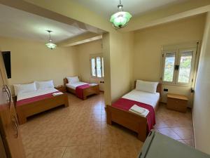 a room with two beds and a tv in it at Hotel Kudhesi in Vlorë