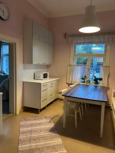 eine Küche mit Tisch und Mikrowelle und Fenster in der Unterkunft Tunnelmallinen Karsikon kansakoulu - jaettu kylpyhuone in Joensuu
