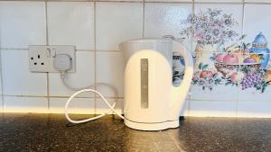 a white appliance sitting on a counter next to a outlet at Budget Stay In Luton 02 05 in Luton