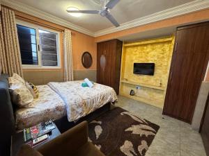 a bedroom with a bed and a tv and a couch at Bays Boutique Apartment in Accra
