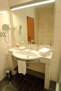 a white bathroom with a sink and a mirror at Hotel Marktkieker in Großburgwedel