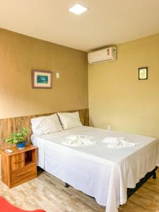 a bedroom with a large white bed with a table at Luamar Chalés in São Miguel do Gostoso +14 photos