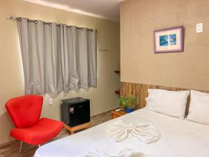 a bedroom with a bed and a red chair at Luamar Chalés in São Miguel do Gostoso
