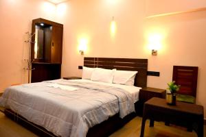 a bedroom with a large bed with white sheets at Zayana Gardens Family Private Room in Anachal +7 photos