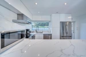 a white kitchen with a stainless steel refrigerator at Modern House Close to the Beach in Deerfield Beach