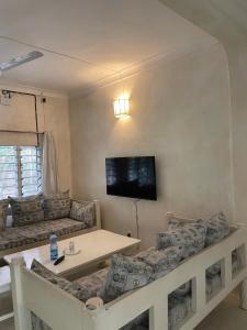 a living room with couches and a tv on the wall at Watamu 2B in Watamu