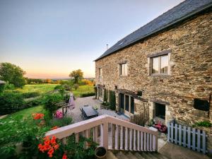a stone house with a porch and a balcony at La Source Du Bonheur Chambres et Table d'Hôtes in Rieupeyroux