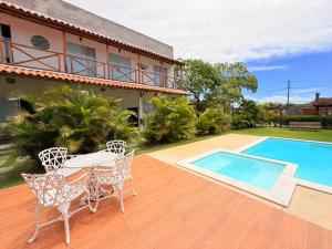 a patio with a table and chairs and a swimming pool at Pousada Villa Egregora in Itacimirim