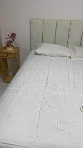 a large white bed in a room with a table at Hostel da Dinda in São Luís