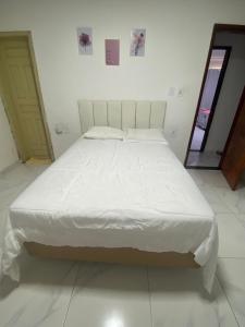 Cama grande en habitación con colcha blanca en Hostel da Dinda, en São Luís