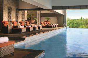 um átrio do hotel com uma piscina com cadeiras laranja e uma piscina em Gokulam Grand Hotel & Spa Bangalore em Bangalore