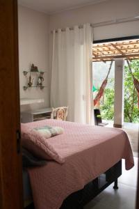a bedroom with a bed with a pink blanket and a window at Refúgio encanto das montanhas in Nova Friburgo