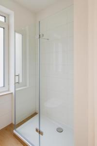 a glass shower in a bathroom with a window at City Apartments in Osnabrück in Osnabrück