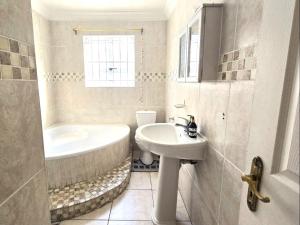 a white bathroom with a tub and a sink at Langebaan at Amorgos 3 in Langebaan +2 photos
