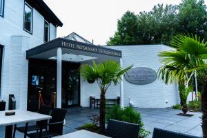 Un restaurante con mesas y sillas frente a un edificio. en Hotel De Elderschans, en Aardenburg
