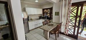 a kitchen with a table with chairs and a counter top at Casa Canto do Mar Maresias 2 in Maresias